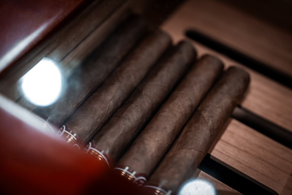 Hand-rolled cigars lining a wooden humidor under warm amber light